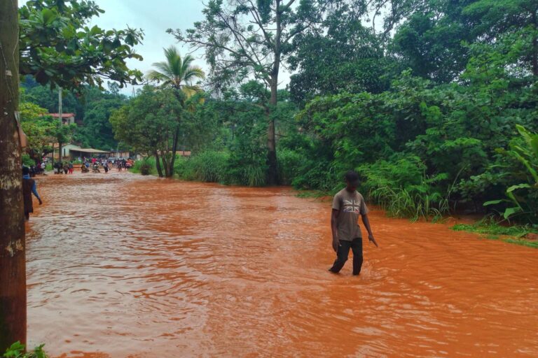 WMO Regional Association for Africa to strengthen early warning systems A man wades through knee-high orange water in Africa.