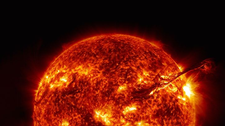 A close up of the sun viewed from the space, with solar storms and flares visible across its surface. Space is dark and black in the background
