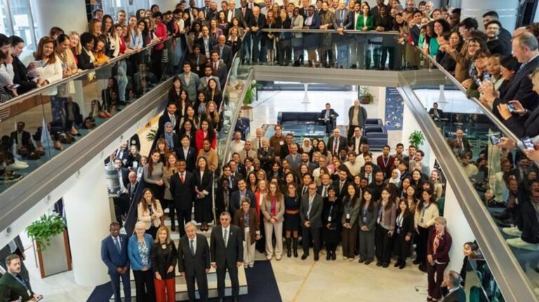 UN Secretary-General calls for rapid expansion of early warning systems at WMO Congress Group photo at the WMO Congress, with delegates standing together, some on the conference floor, some on stairs and some on the overlooking level above