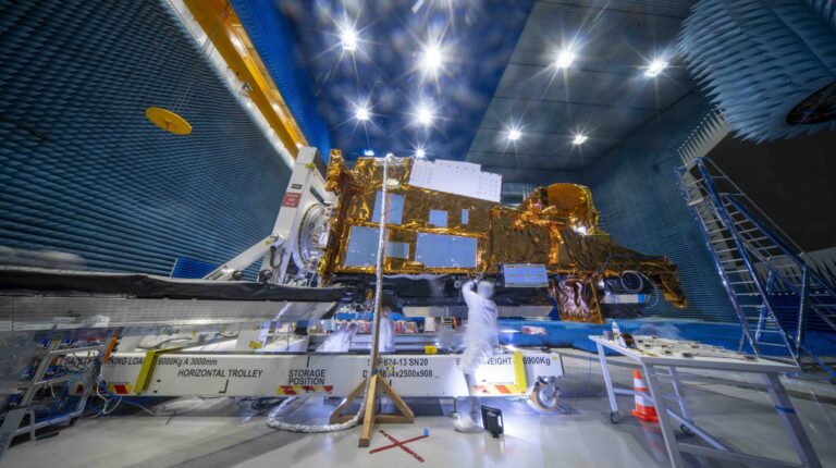 MetOp-SG-B1 satellite enters third round of pre-launch tests ahead of 2026 launch The MetOp-SG-B1 satellite – with white metal structure and bright gold pieces – undergoing tests in a large warehouse space, with a high ceiling a a scientists in the foreground in white overalls