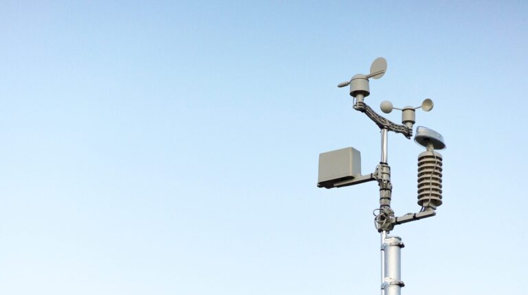 A weather station reaches up into a blue-cloudless sky.