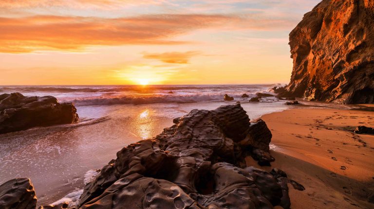 WMO forecasts rapid strengthening of El Niño, warns of extreme weather risks Natural sea arch at Hole in the Wall Beach in California during sunset, warm golden light illuminating rugged coastal rock, ocean waves and smooth sand, creating dramatic seaside landscape