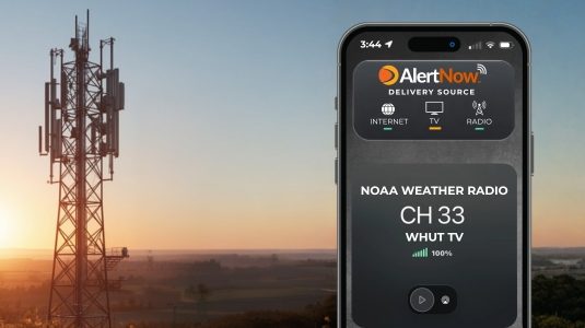 NOAA and SpectraRep to evaluate broadcast datacasting for weather radio resiliency Mobile phone displaying SpectraRep's AlertNow app, against a rural background and a large TV signal transmitter.
