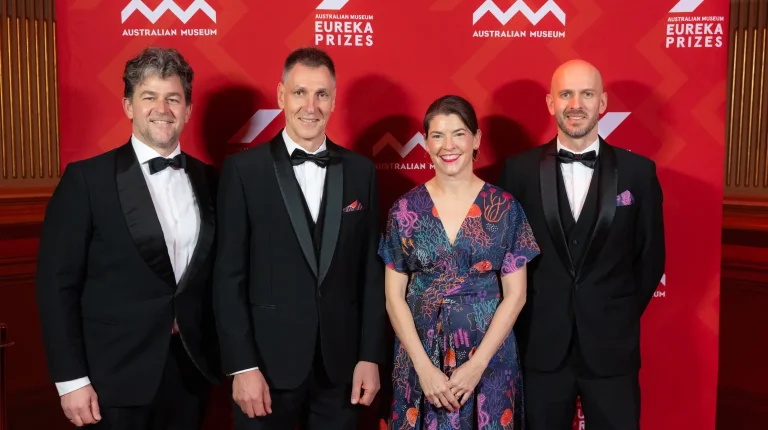 Dr Claire Spillman and Dr Grant Smith with CSIRO researchers stand in front of a red background at the award of the Eureka Prize